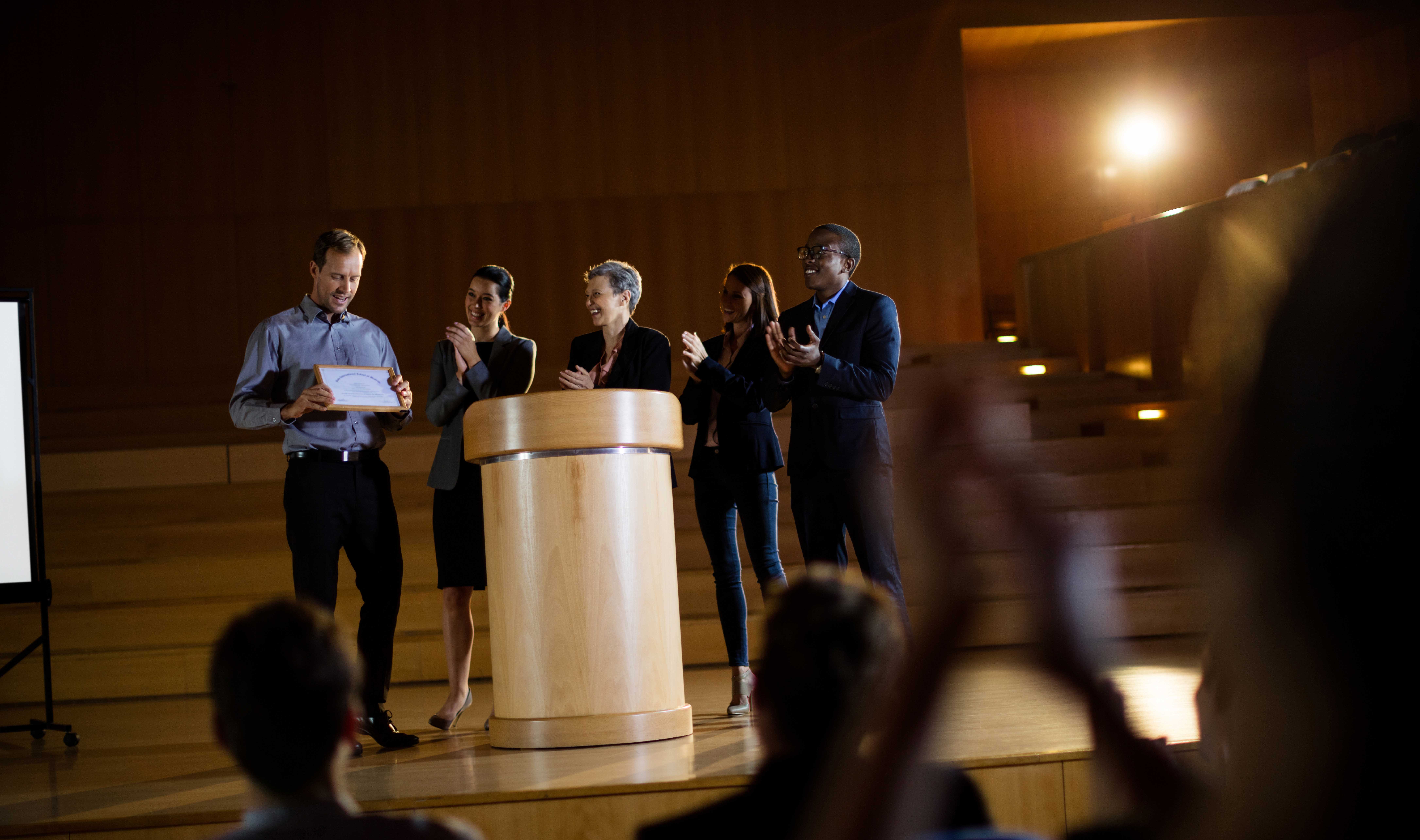 Male business executive receiving award at conference center